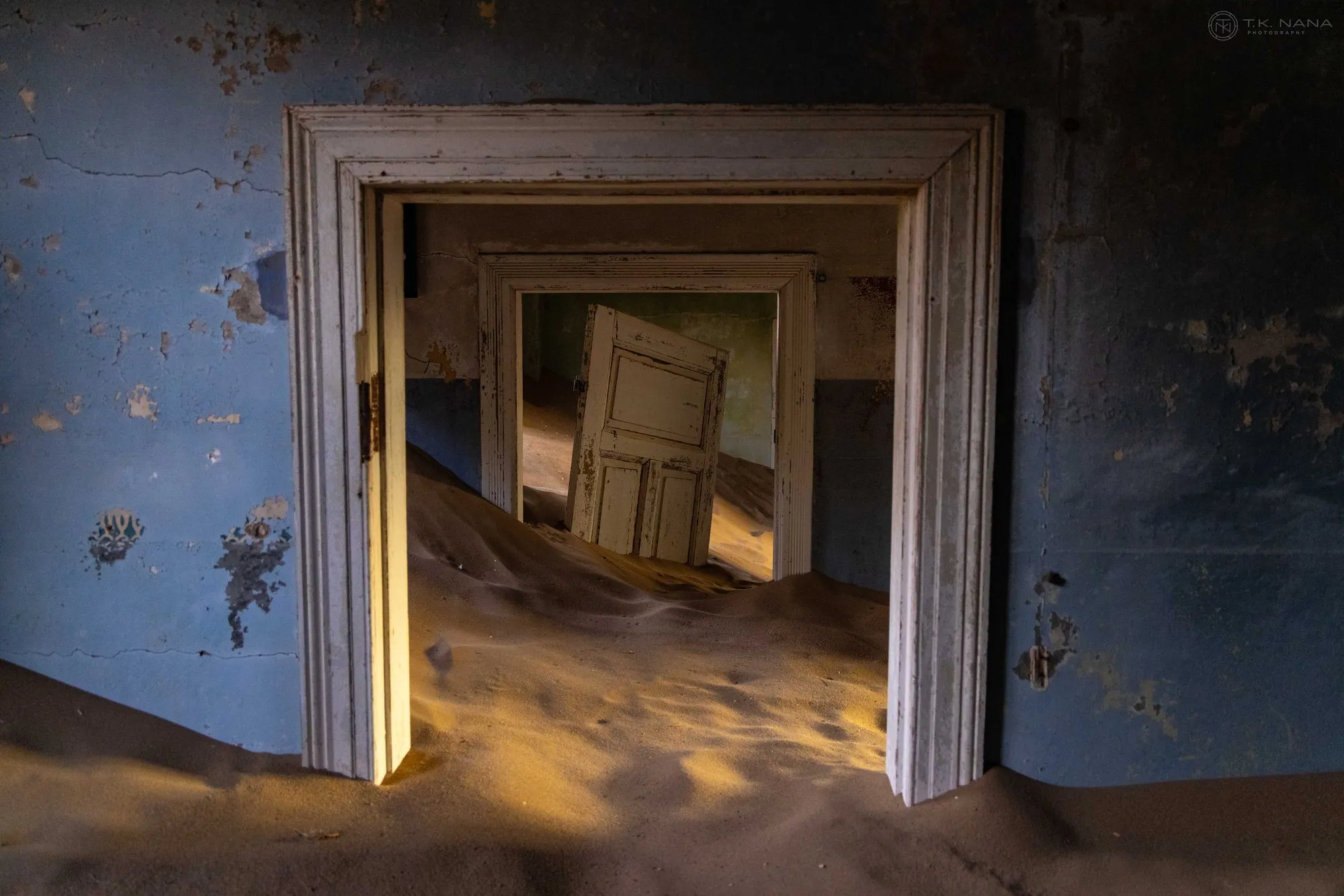 Sand drifting through a doorway in an abandoned house at Kolmanskop