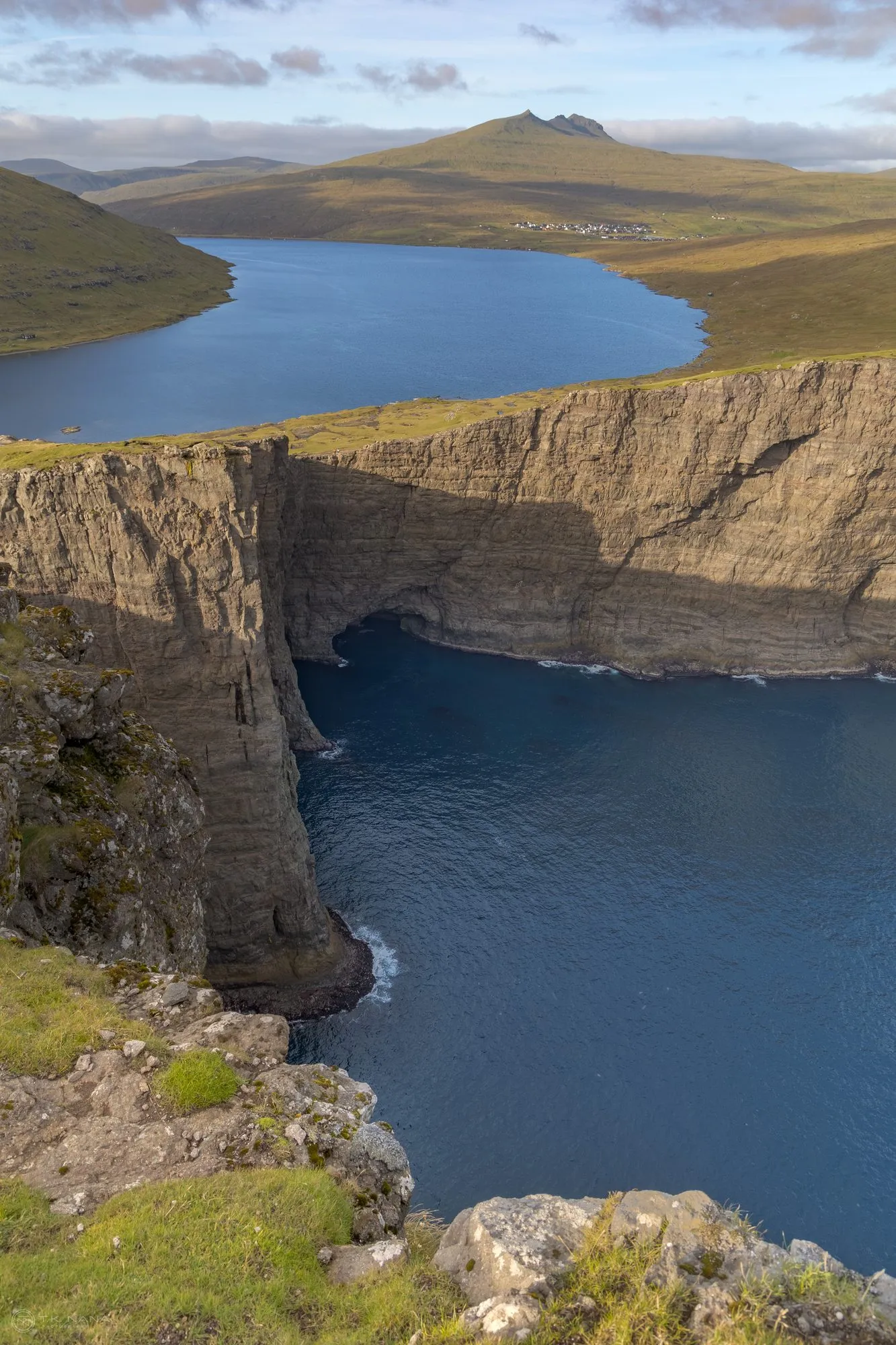 A lake sitting on the cliff edge high above the ocean, vertical frame